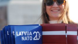 A woman holds Latvian and NATO flags during a flash action to mark the 20th anniversary of Latvia's accession to NATO, at the Freedom Monument in Riga, Latvia, March 28, 2024. Photo: EPA/TOMS KALNINS 