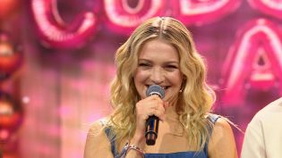 Barbara Kurdej-Szatan, prowadząca program "Cudowne lata" uśmiecha się, trzymając mikrofon. Program rozrywkowy "Cudowne lata" jest dostępny online na TVP VOD.