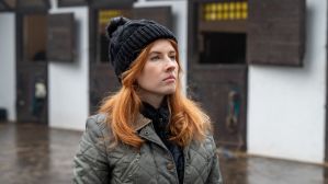 Iga (Paulina Masiak) w ciemnej czapce i pikowanej kurtce stoi przed stajnią, patrząc przed siebie z powagą. W odcinku 728 „Na sygnale” nie zabraknie dramatycznych zwrotów akcji, a los Igi stanie pod znakiem zapytania – serial dostępny w TVP VOD.