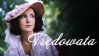 Elżbieta Starostecka jako Stefania, główna bohaterka filmu „Trędowata”. Kobieta ubrana jest w zwiewną fioletową sukienkę oraz kapelusz ozdobiony stokrotkami. Spogląda rozmarzonym wzrokiem w bok, a w tle widoczne są zielone drzewa.