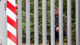 A migrant stands on the Belarusian side of a Polish border barrier. Photo: Attila Husejnow/SOPA Images/LightRocket via Getty Images