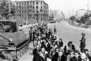 Unwitting civilians, some smiling, are marched from their homes by armed German units. Photo: Bundesarchiv / Wikicommons